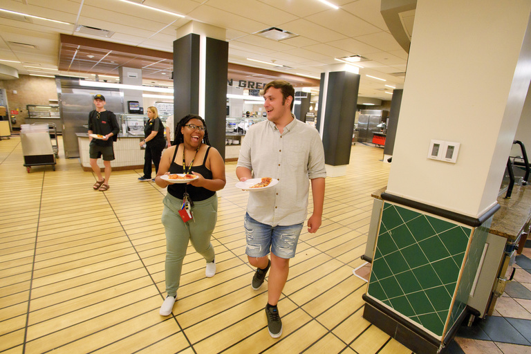 Two students walking with plates of food