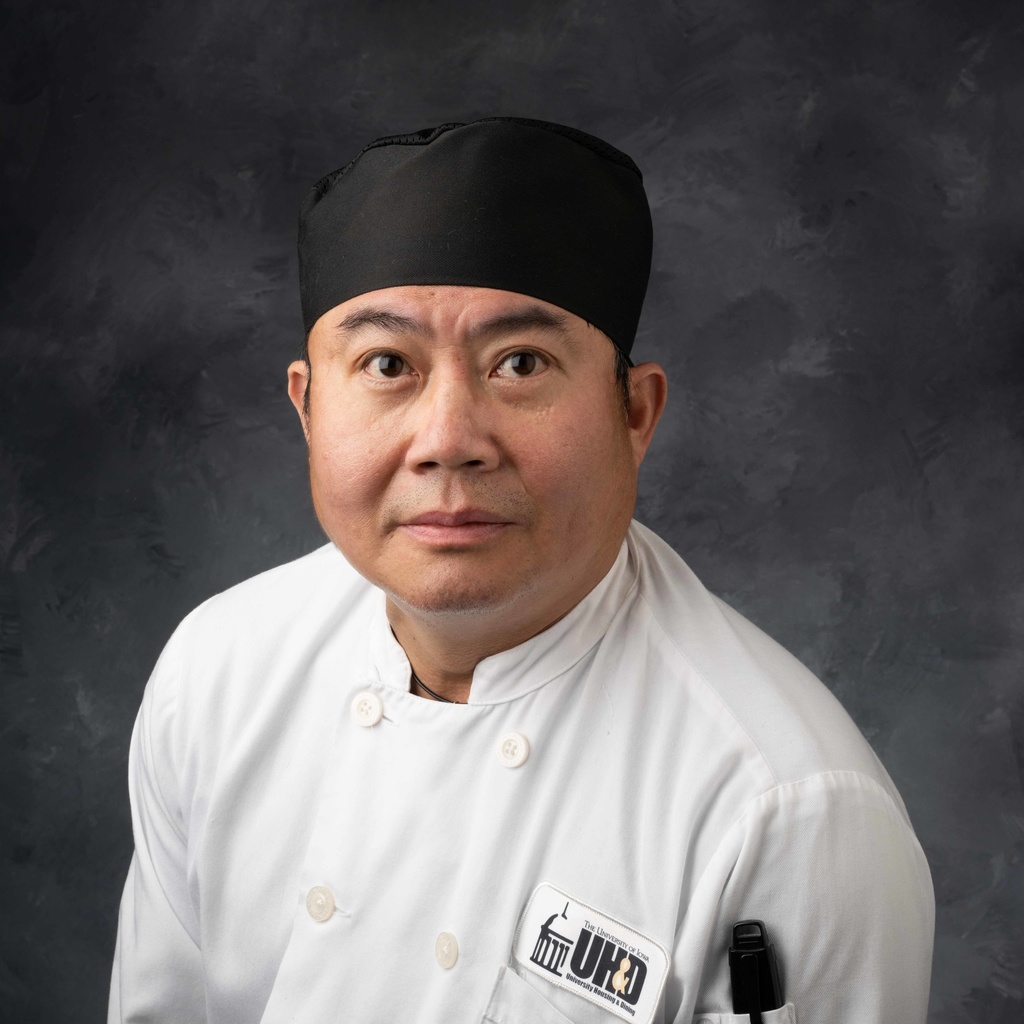Headshot of sous chef Justyn Tran, Vietnamese man wearing white chef's coat