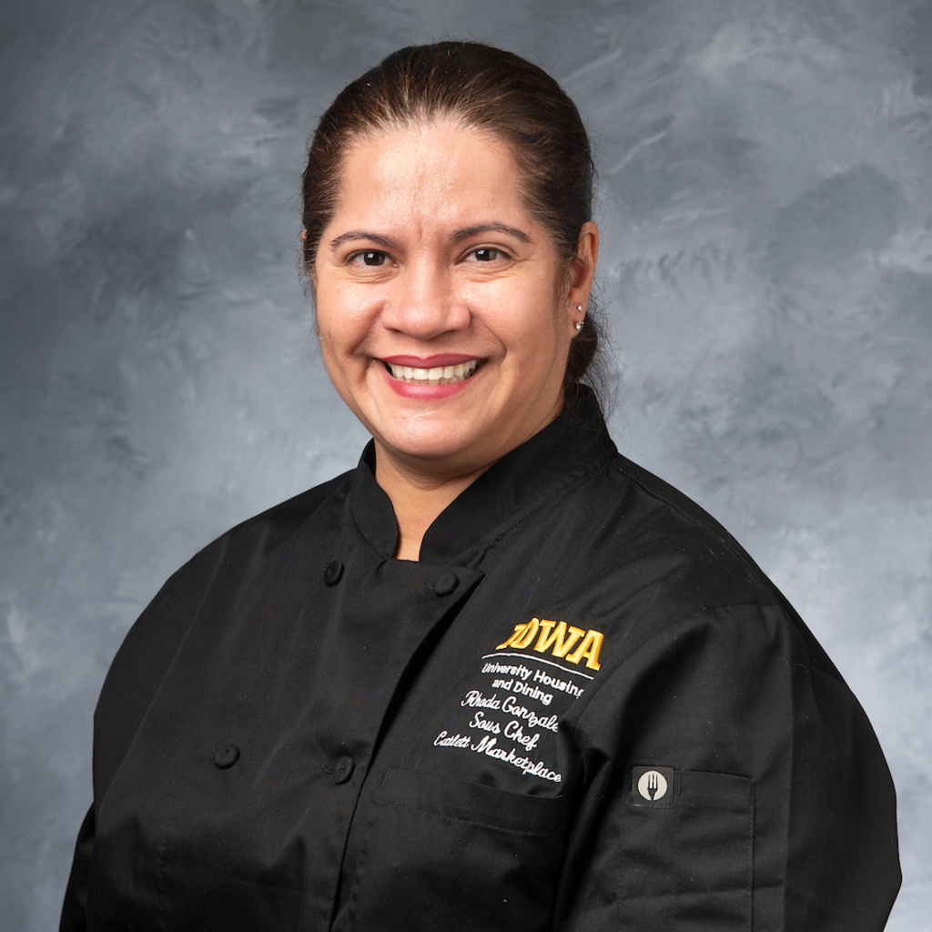 headshot of smiling Latina woman in black chef's coat
