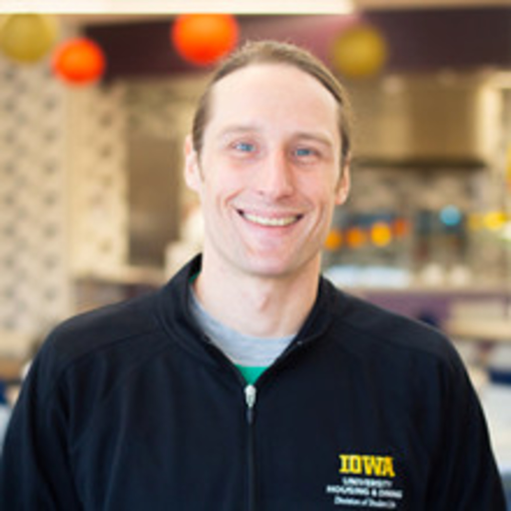 Chef Tim Reicks headshot, white man smiling in Catlett Market Place wearing black chef's coat