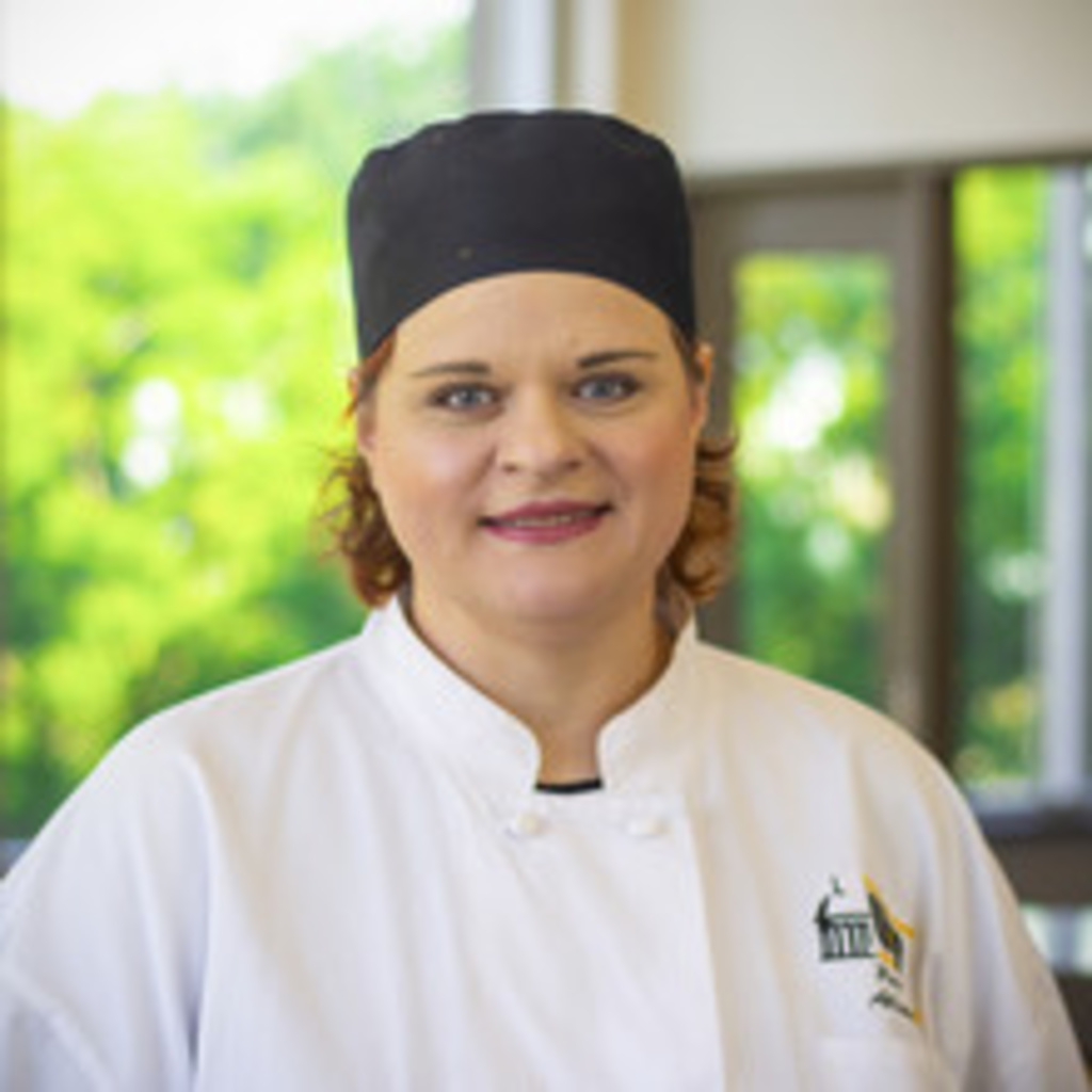 headshot of Alison Kosek, wearing black chef's cap and white chef's coat