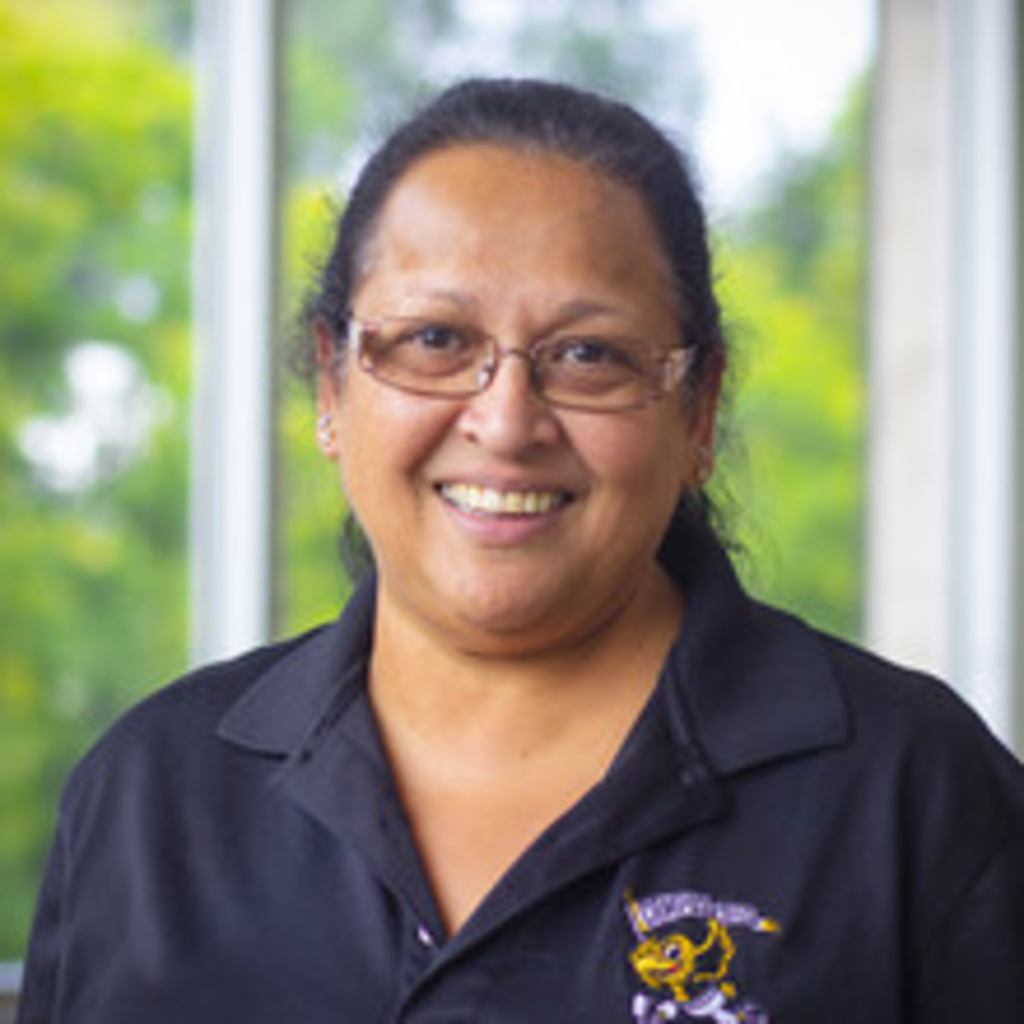 headshot of retail manager Kiku, a woman with hair in ponytail, wearing black polo shirt and glasses