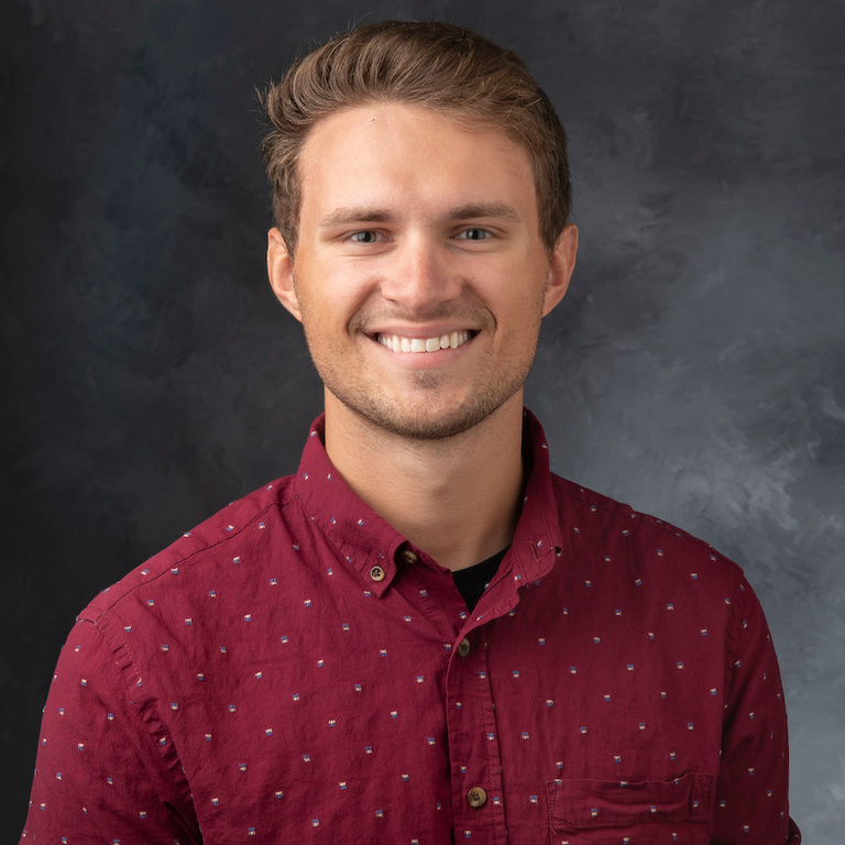 headshot of white man, sandy brown hair with burgundy buttondown