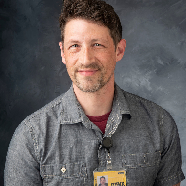 headshot of assistant manager Nick Meister, white man wearing gray buttondwn