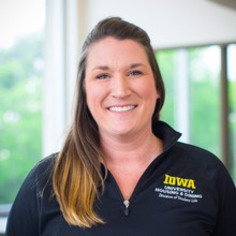 headshot of operations manager Darby Seymour, smiling white woman with sandy brown hair wearing a black UHD quarter zip