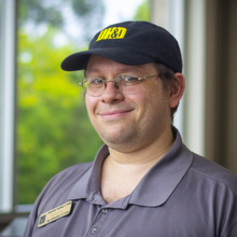 headshot of manager Terry, white man with glasses wearing a black UHD ballcap and gray UHD polo shirt