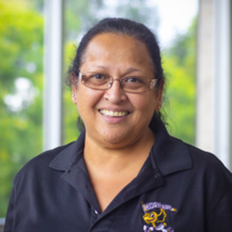 headshot of retail manager Kiku, a woman with hair in ponytail, wearing black polo shirt and glasses